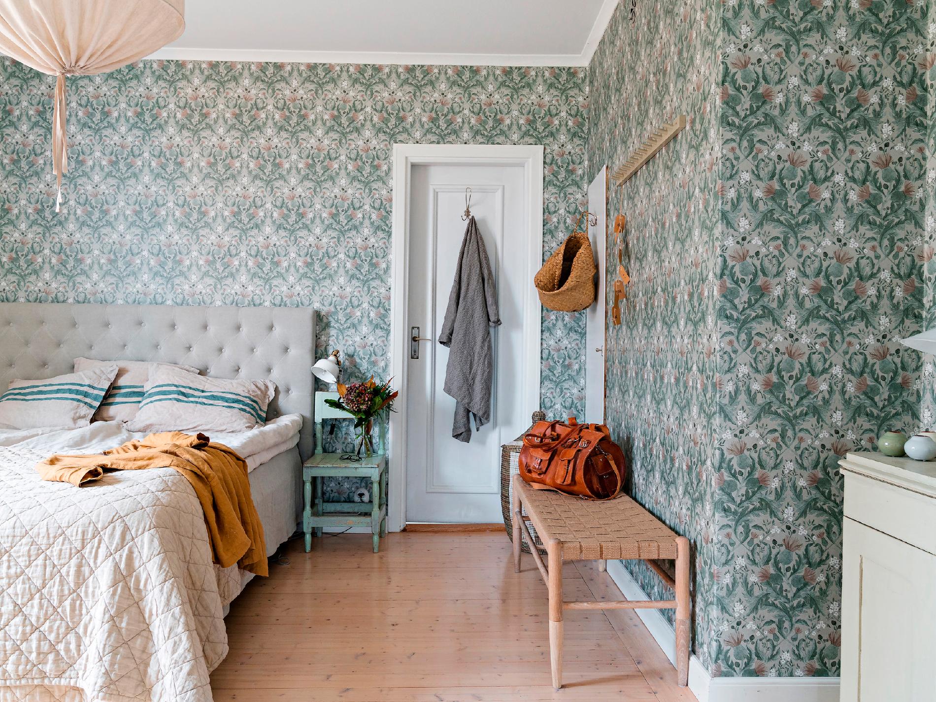Fridas och Anders sovrum har fått en remake med tapeten Thistle från Boråstapeter som går i svala dämpade nyaser av grått och blågrönt.  Textilier i mjuka beige nyanser gör rummet harmoniskt och vilsamt.