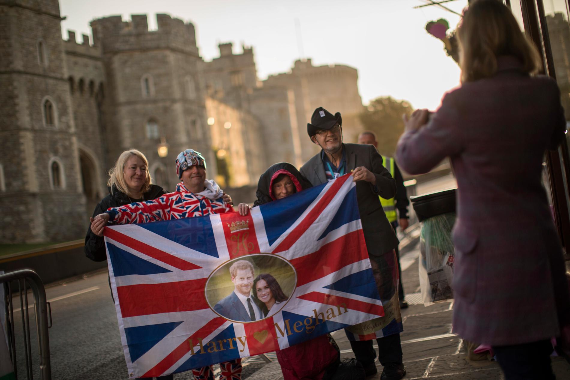 Glada bröllopsfirare håller upp den brittiska flaggan med Meghan Markle och prins Harry, utanför Windsor slott – där bröllopet hålls på lördagen. 