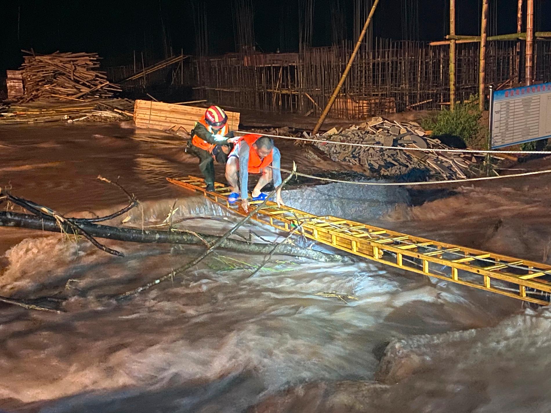 En räddningsarbetare hjälper en man att ta sig över ett översvämmat område i den kinesiska provinsen Jiangxi.