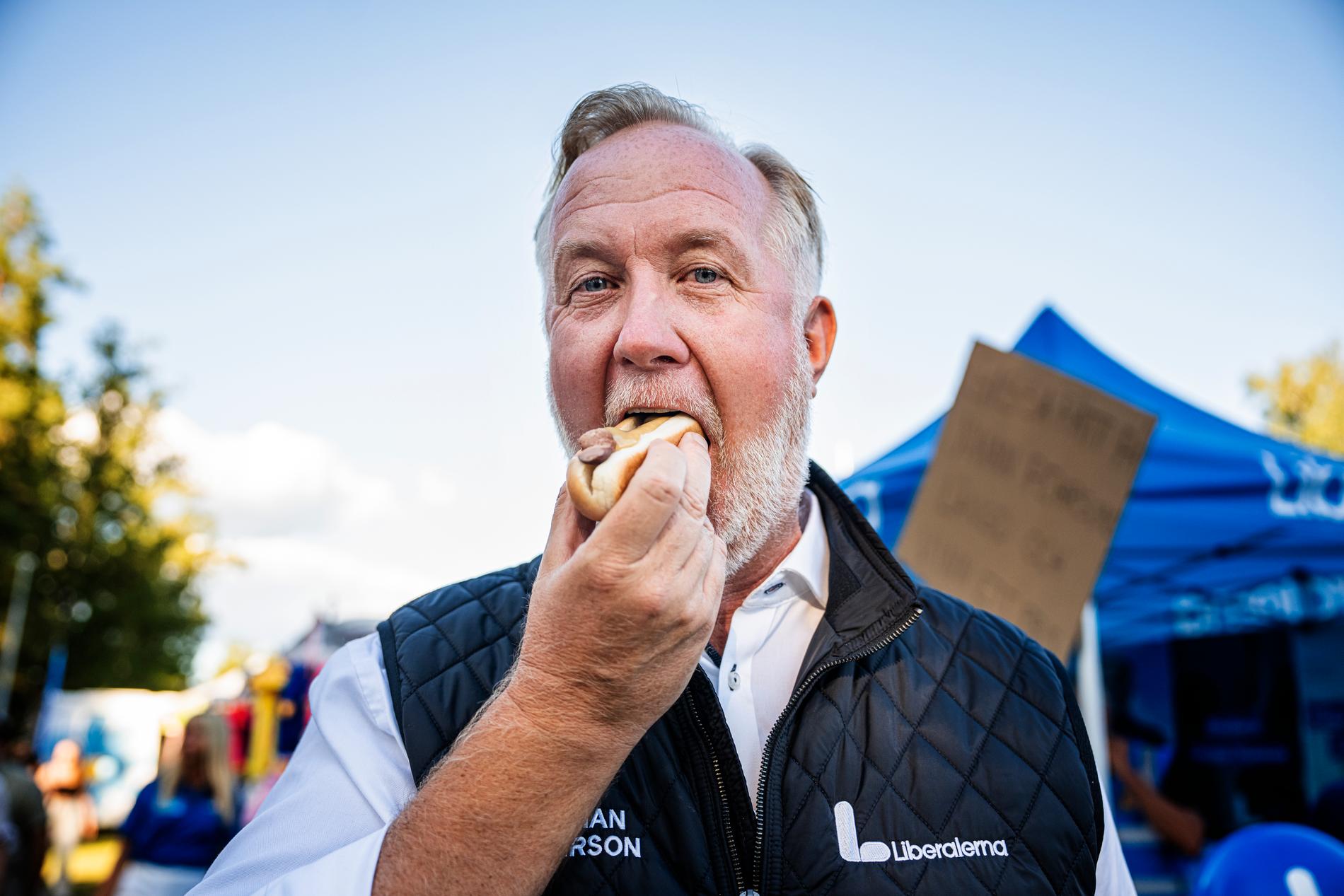 Johan Pehrson äter kokt korv med bröd under sin valkampanj. 