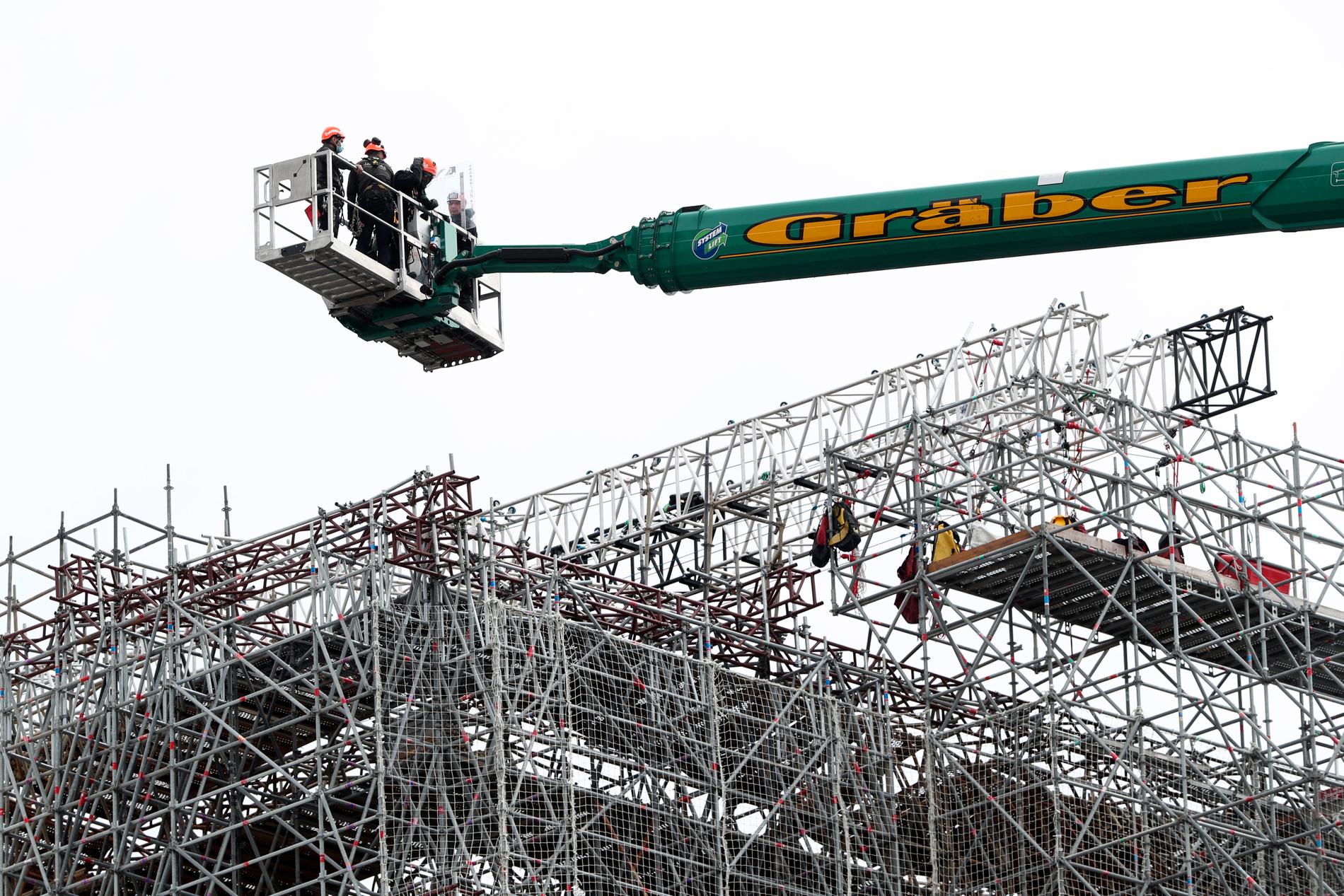 Arbetare lyftes upp till Notre-Dame för att inleda arbetet med att avlägsna de smälta byggnadsställningarna under måndagen.