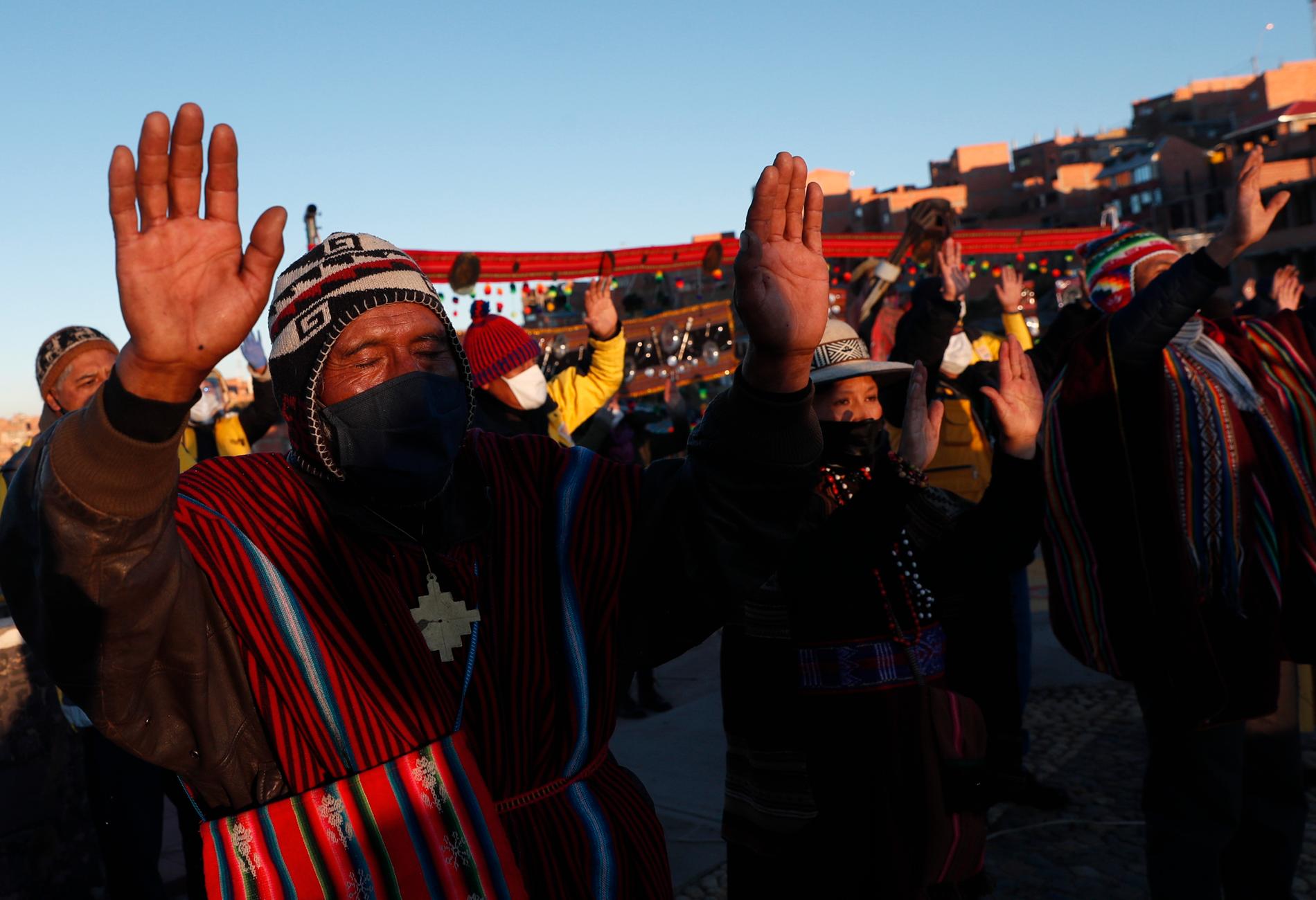 Människor tillhörande ursprungsfolket aymara bär skyddsmasker under en ceremoni för att fira solen i La Paz, Bolivia.