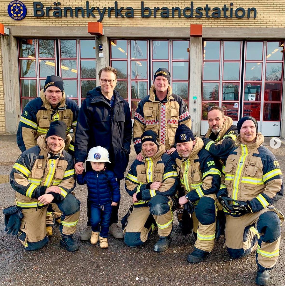 Här poserar prins Oscar och pappan prins Daniel med brandmännen på Brännkyrka brandstation. 