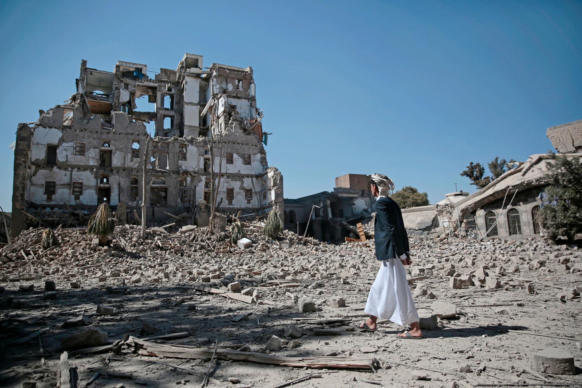Huthirebell vid resterna av ett palats som bombats av den saudiskledda militäralliansen i Sanaa. Arkivbild.