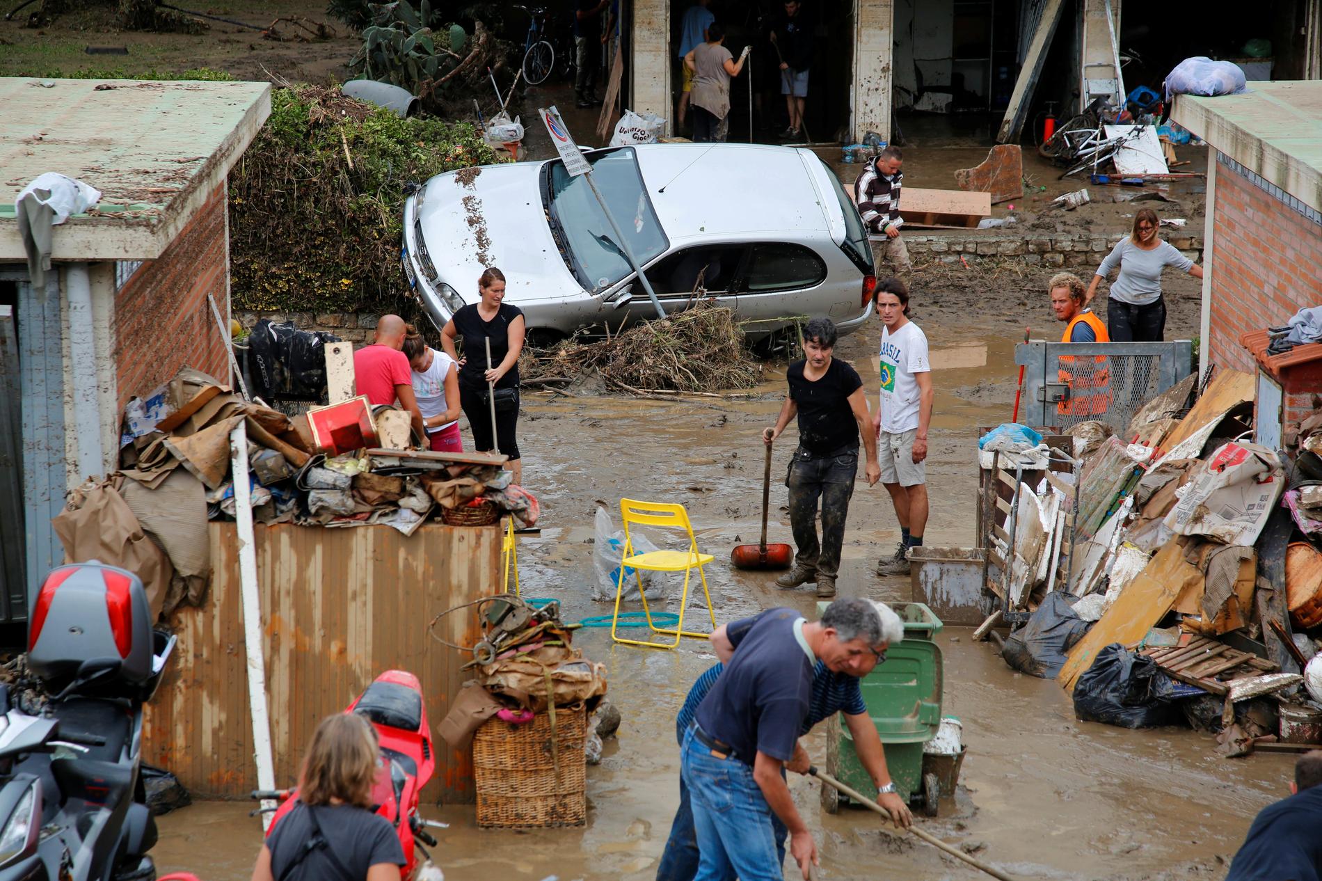 Boende i Livorno hjälps åt att röja upp efter översvämningarna. 