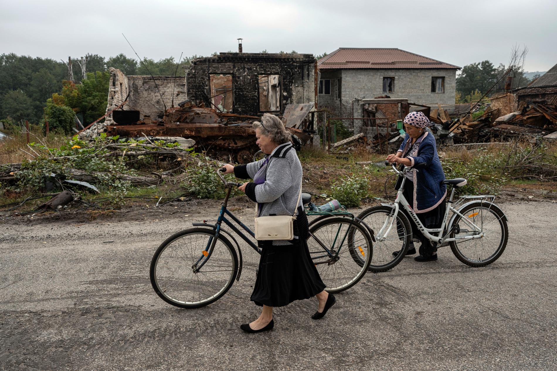 2 OKTOBER: Kvinnor promenerar förbi raserade hus i Izium.