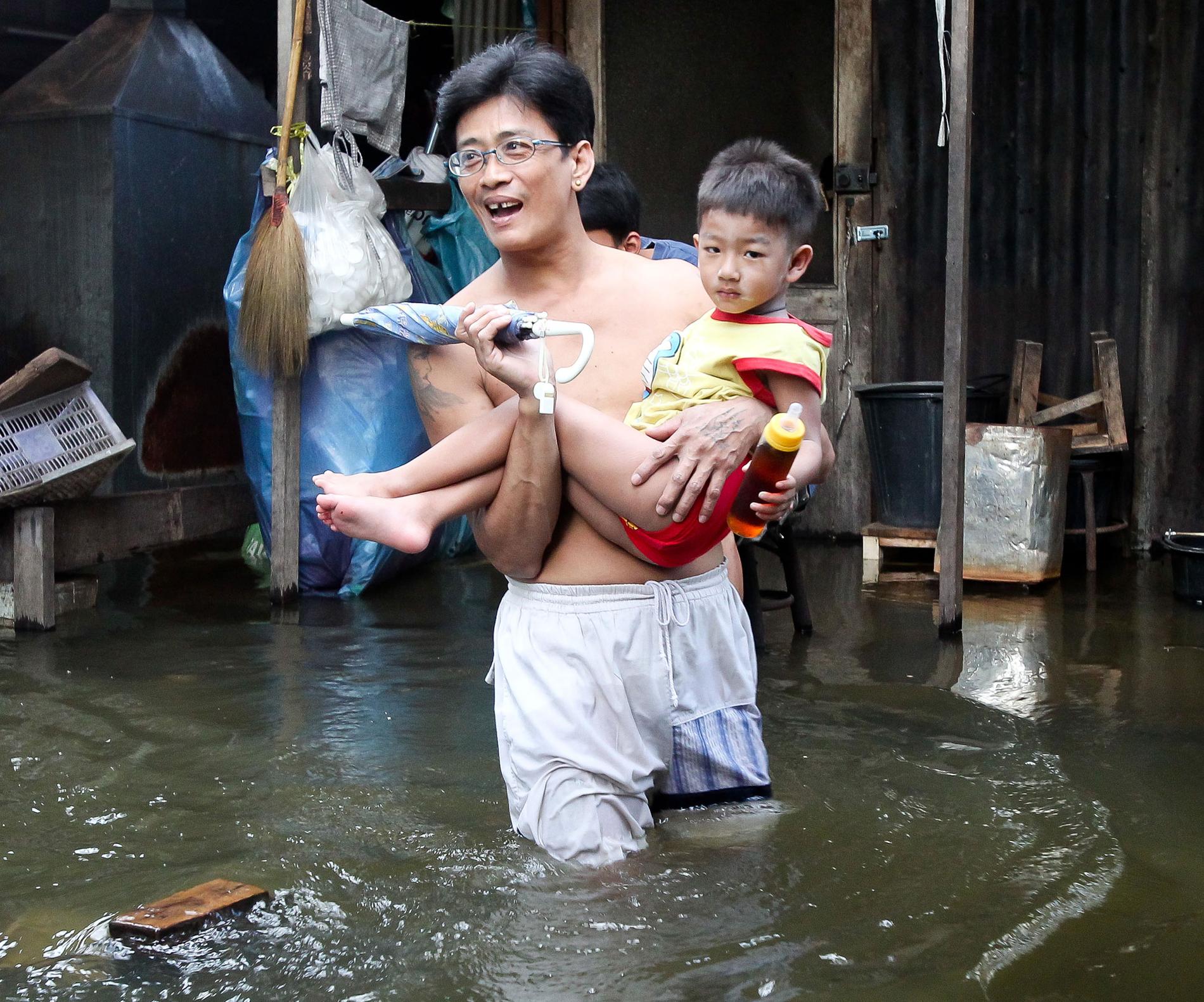 DRABBAS FÖRST. Far och son kämpar sig genom vattenmassorna i Bangkok i Thailand. Landet drabbades hårt av det kraftiga sommar­regnet i slutet av förra året. Asien och Stillahavsområdet påverkas mest av klimatförändringarna.Foto: Dennis THERN