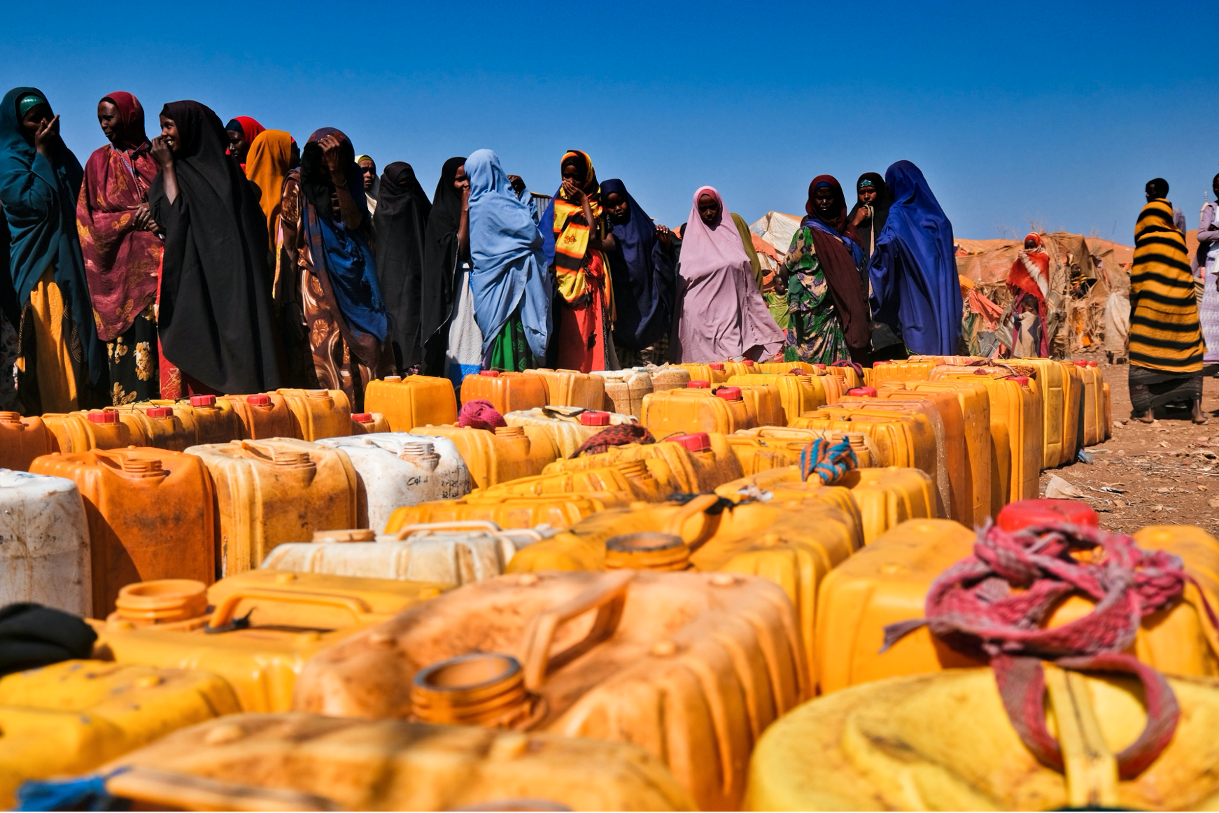 Kvinnor som drivits på flykt av torkan väntar på vattendunkar.