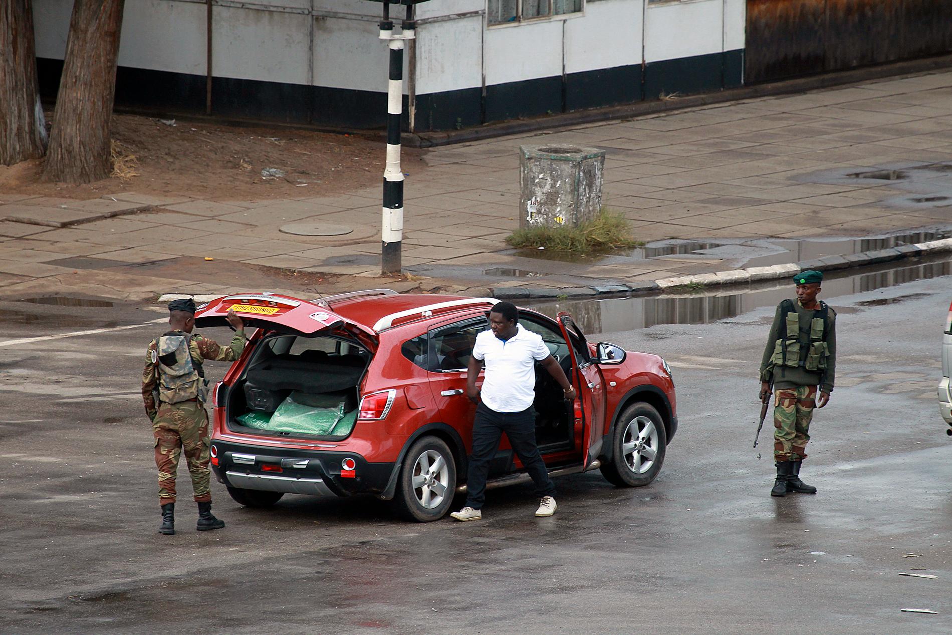 Militär letar igenom en bil på en gata som leder till Robert Mugabes högkvarter i Zimbabwes huvudstad Harare.