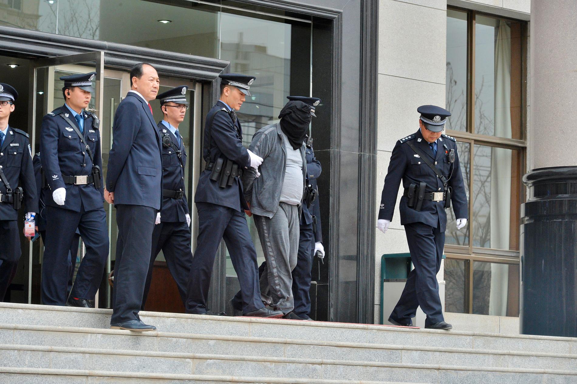 Gao Chengyong eskorteras av poliser utanför rätten. 