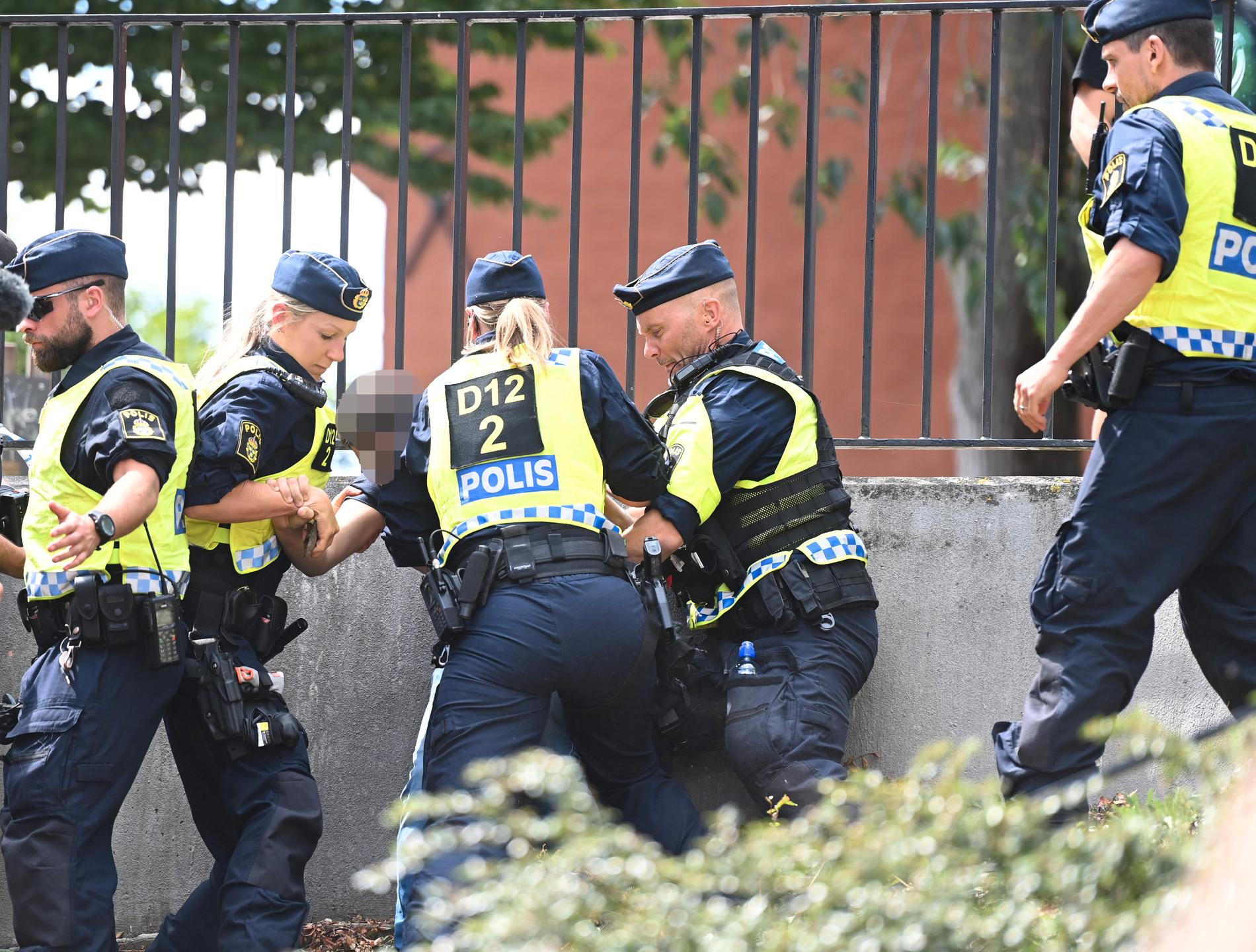 En man omhändertas av polisen vid koranbränningen i Stockholm. 
