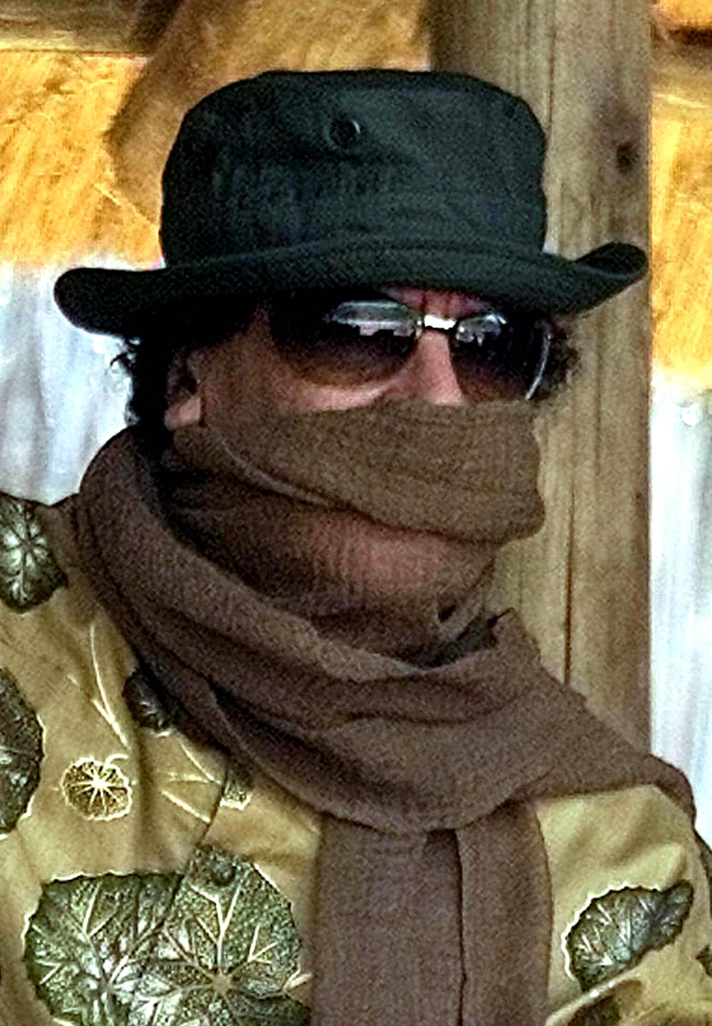 Muammar Gaddafi skyddar sig mot sanden med en scarf under ett besök i Swaziland.