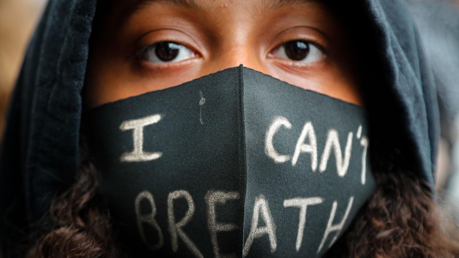 En flicka med munskydd under lördagens Black Lives Matter-demonstration i London. På munskyddet står det "jag kan inte andas" – de ord den svarte amerikanen George Floyd sade när en polisman sitt knä mot hans nacke. Floyd avled kort därpå.