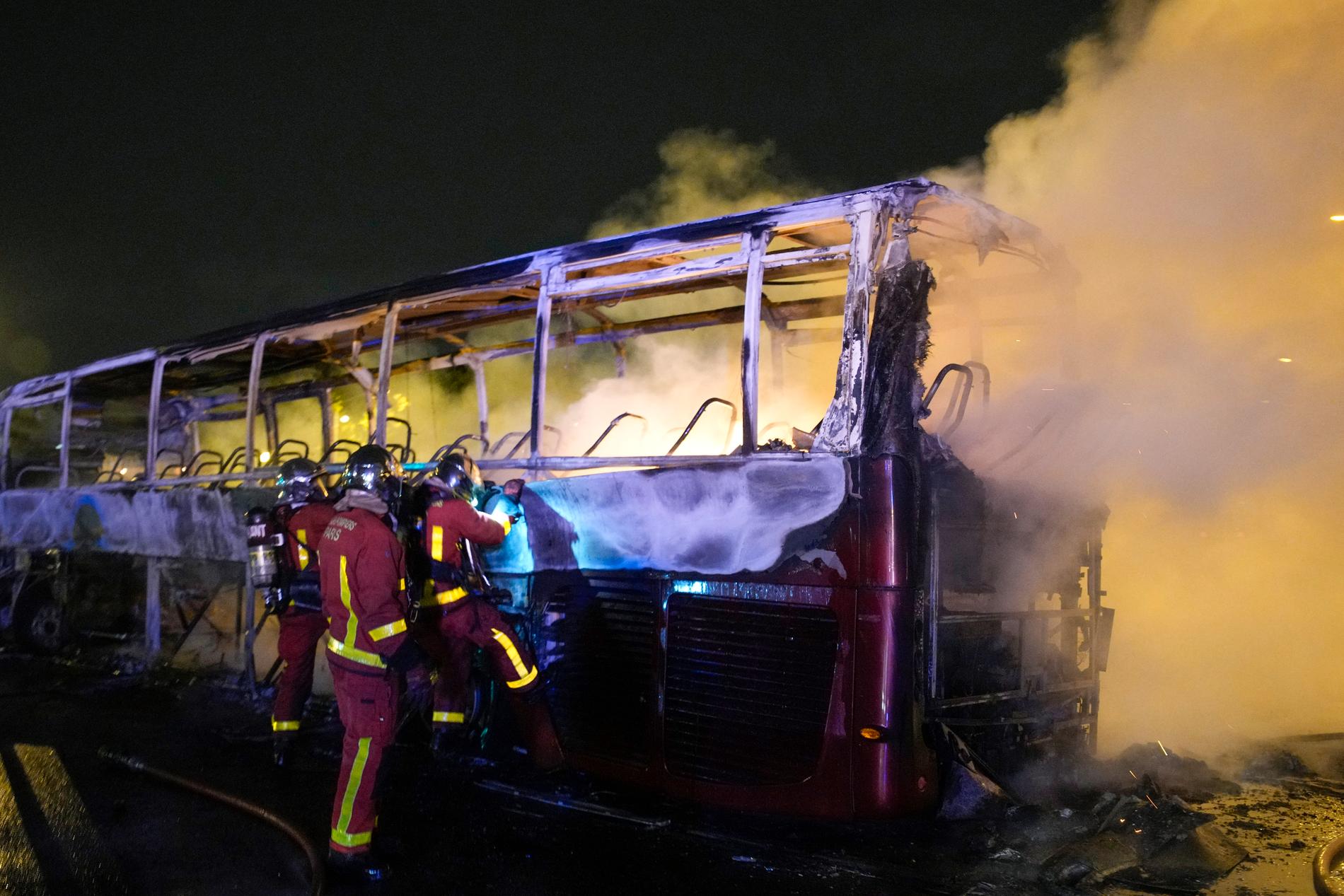 Räddningstjänsten försöker släcka en brinnande buss under natten till lördag i Parisförorten Nanterre.