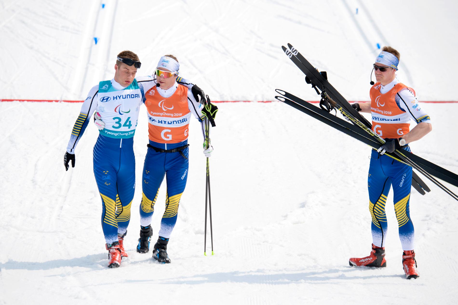 Zebastian Modin, till vänster, i målfållan efter medaljmissen på 20 kilometer. Guiderna Robin Bryntesson, håller om Modin, och Johannes Andersson försöker trösta.