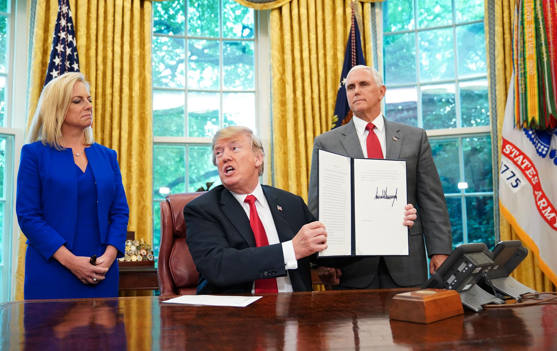 President Donald Trump håller upp den undertecknade ordern. 