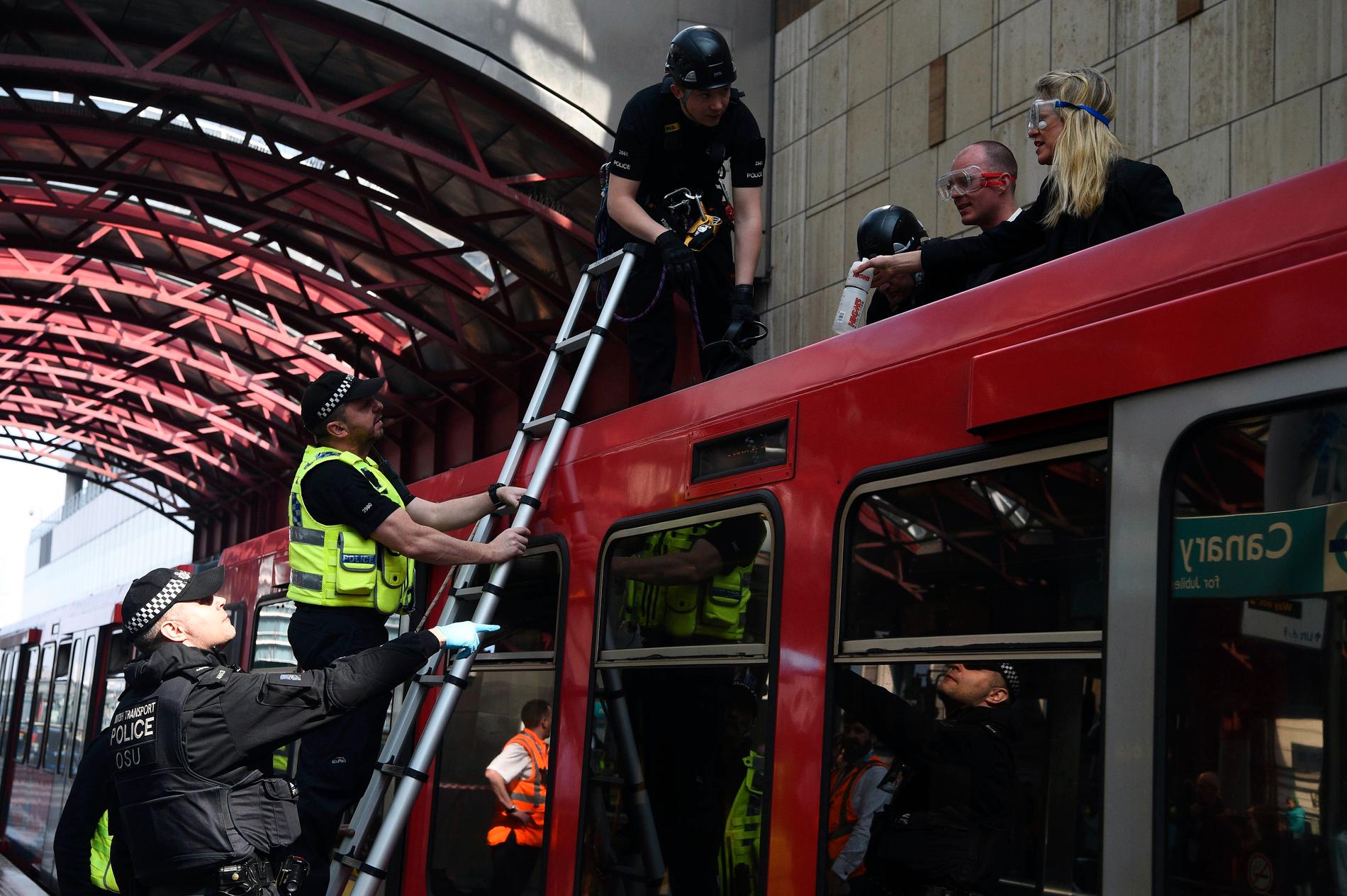 Två demonstranter har klistrat fast sig i ett tåg på stationen Canary Warf i östra London.