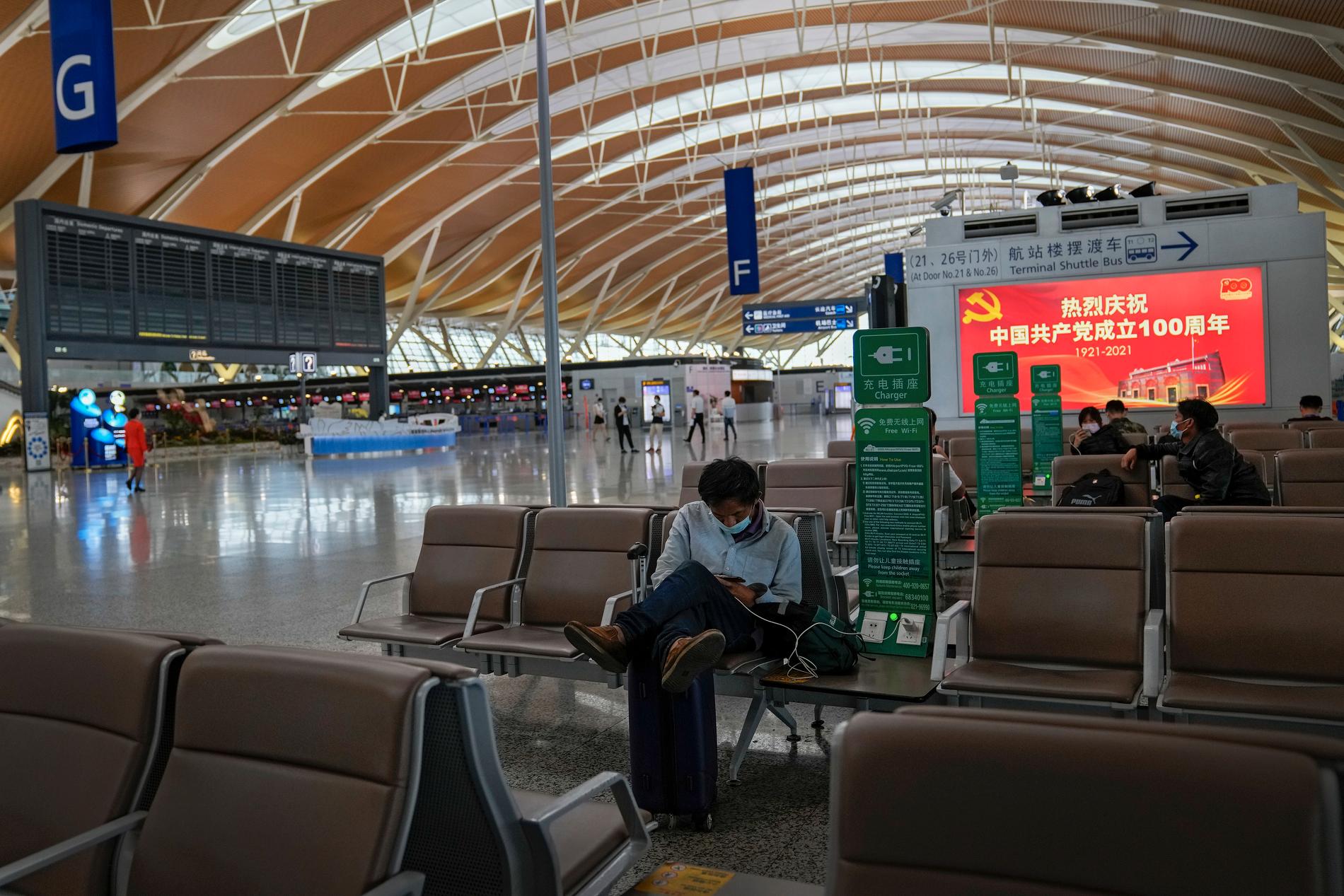Passagerare väntar vid tomma informationstavlor på Pudong-flygplatsen i Shanghai. Alla flygningar ställdes in på stadens två internationella flygplatser på söndagen på grund av tyfonen In-fa.