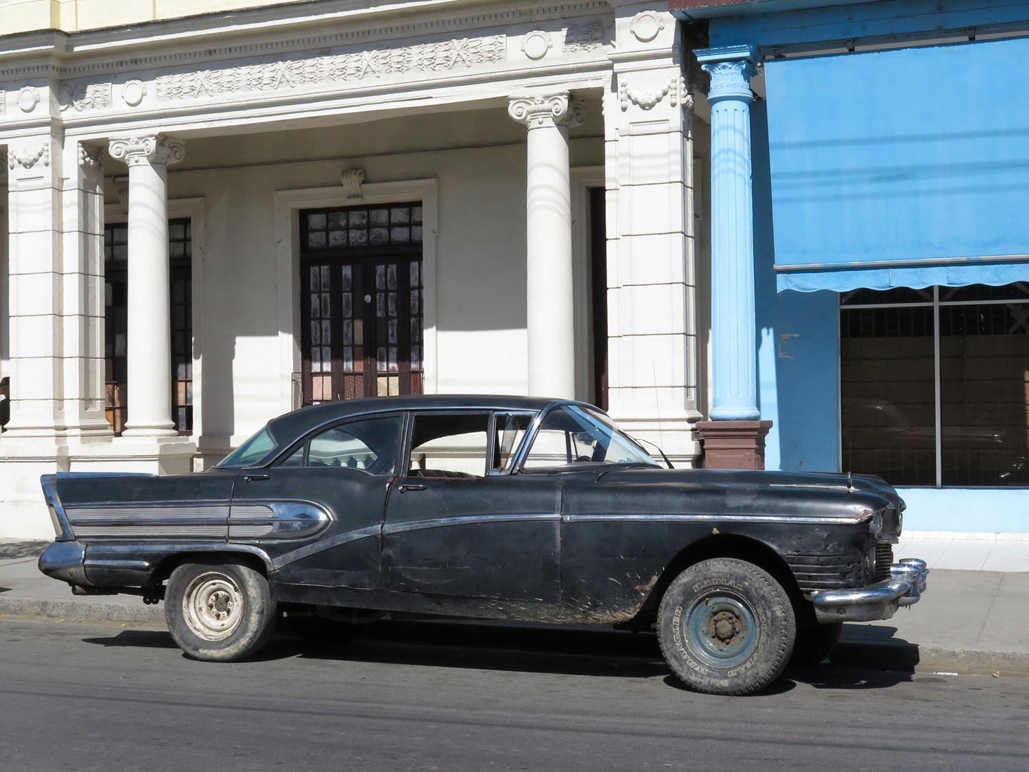 En skitig och mycket tidig skogsmulle parkerad på huvudgatan i Palmira utanför storstaden Cienfuegos. Kolla in markfrigången och stora hjul som ägaren monterat på sin Buick Roadmaster, kanske från 1958.