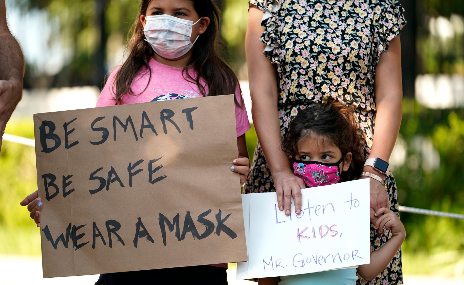 Demonstrationer i Austin mot att Texas guvernör Greg Abbott förbjudit lokala skolor från att utfärda munskyddskrav. Nu har Abbott själv testat positivt för covid-19.