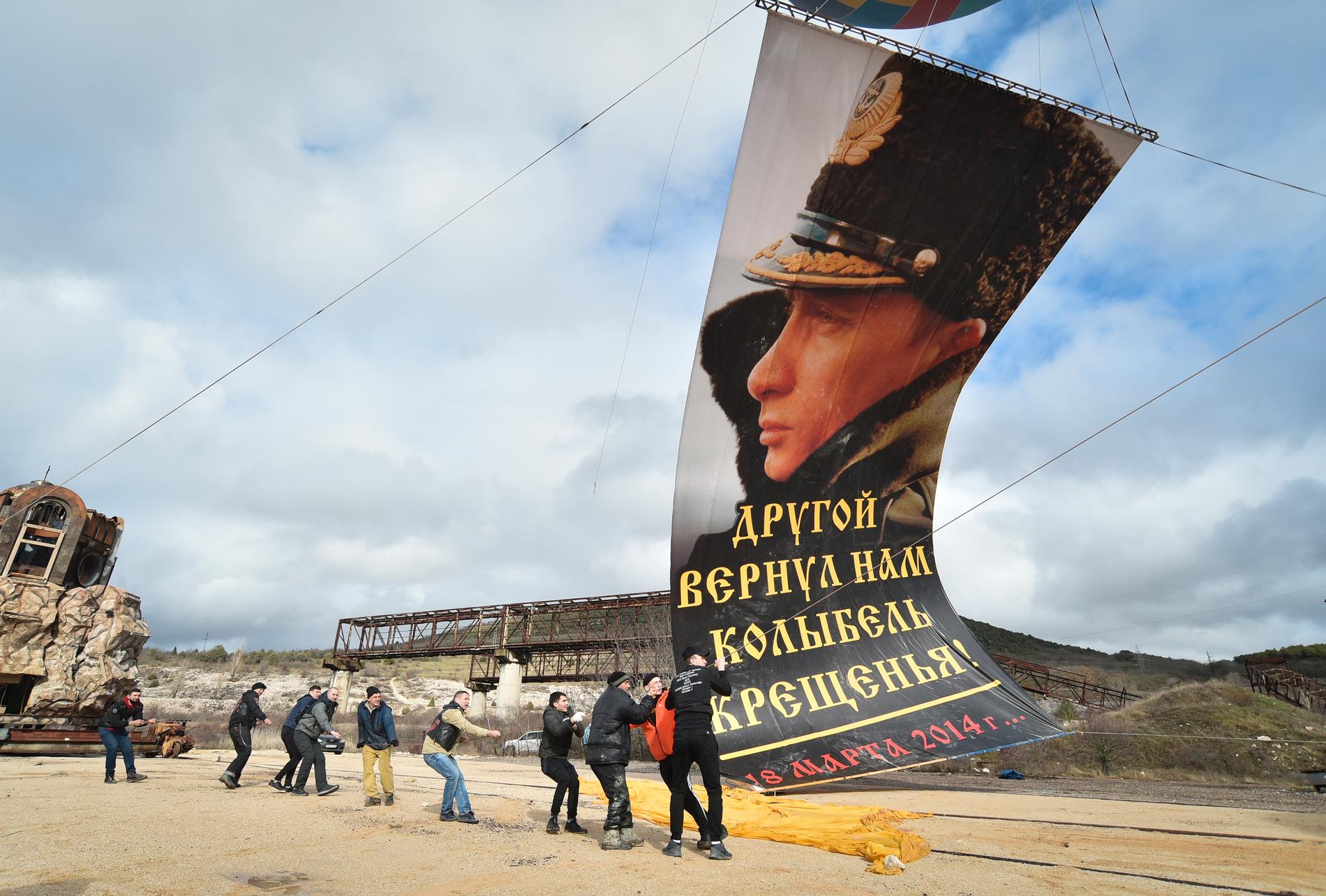 I staden Sevastopol på ukrainska Krimhalvön, monteras en flagga på Rysslands president Vladimir Putin med texten "En annan gav oss åter dopets vagga" på sjuårsdagen av den ryska annekteringen av Krim i mars i år.