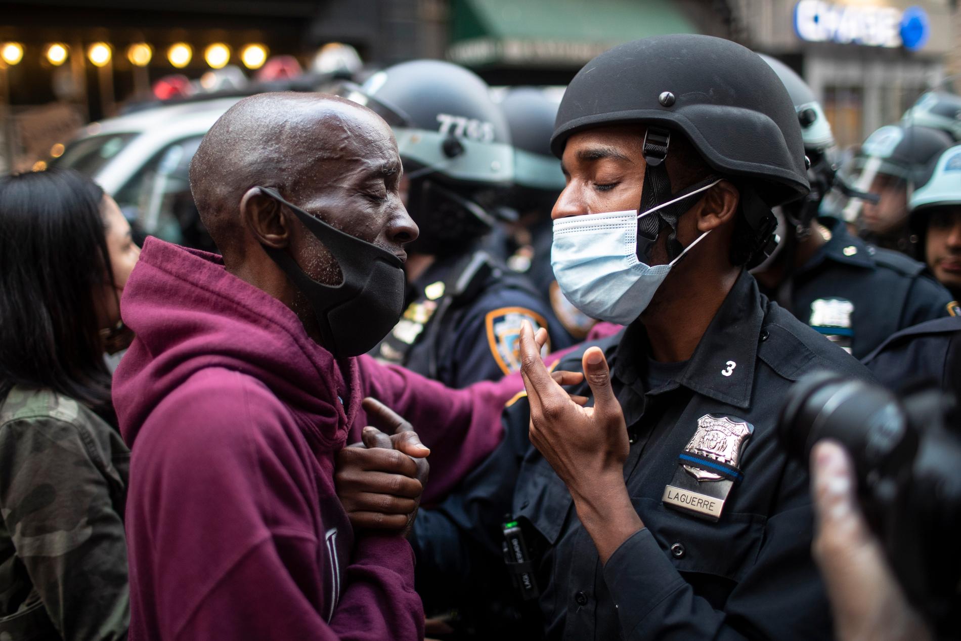 En demonstrant och en polis skakar hand under tisdagens protester i New York.