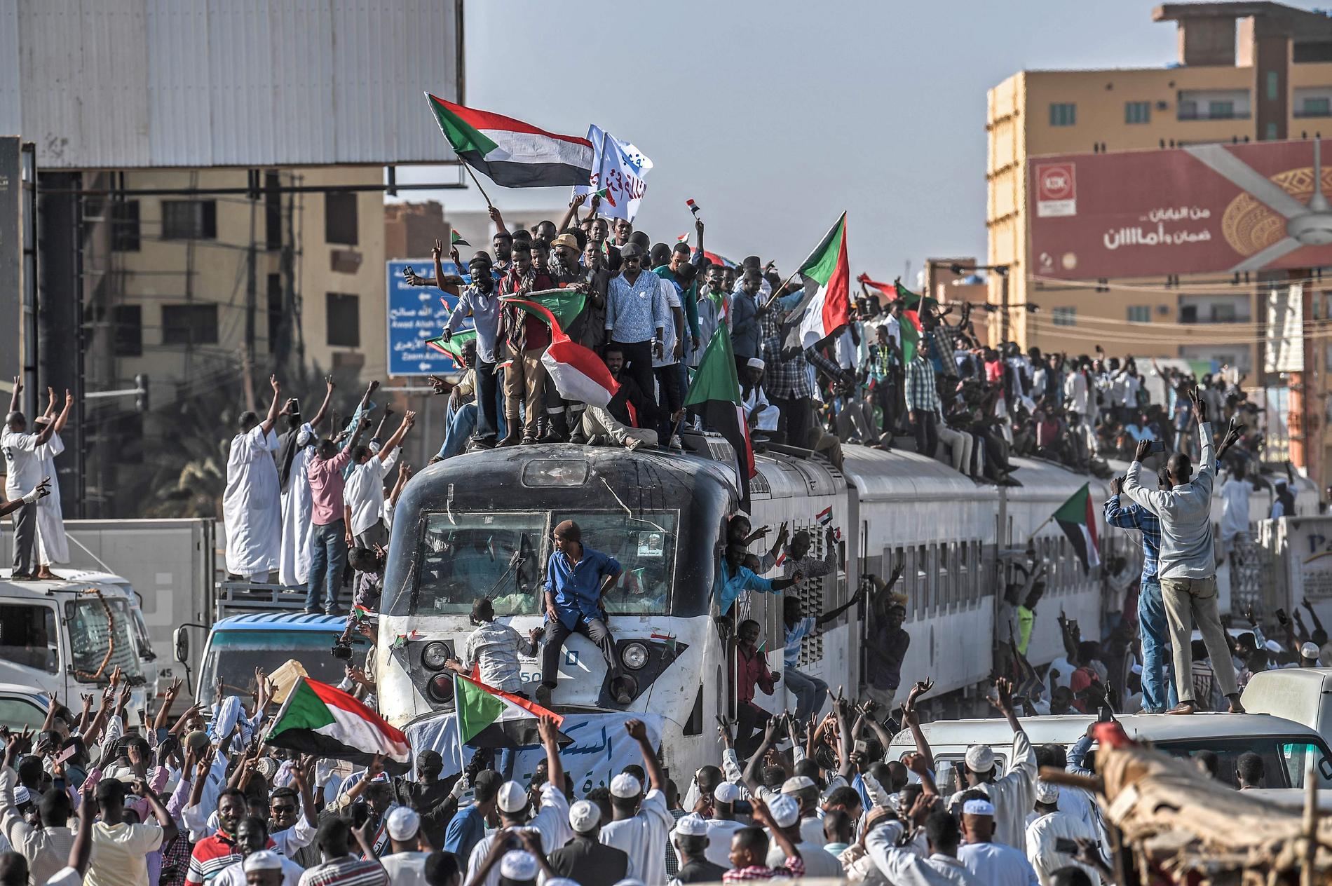 Demonstranter som kommer med tåg till Sudans huvudstad Khartum tas emot av jublande likasinnade.