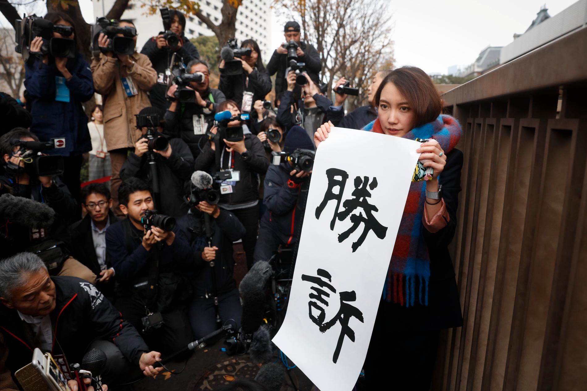 Shiori Ito håller upp en banderoll under presskonferensen.