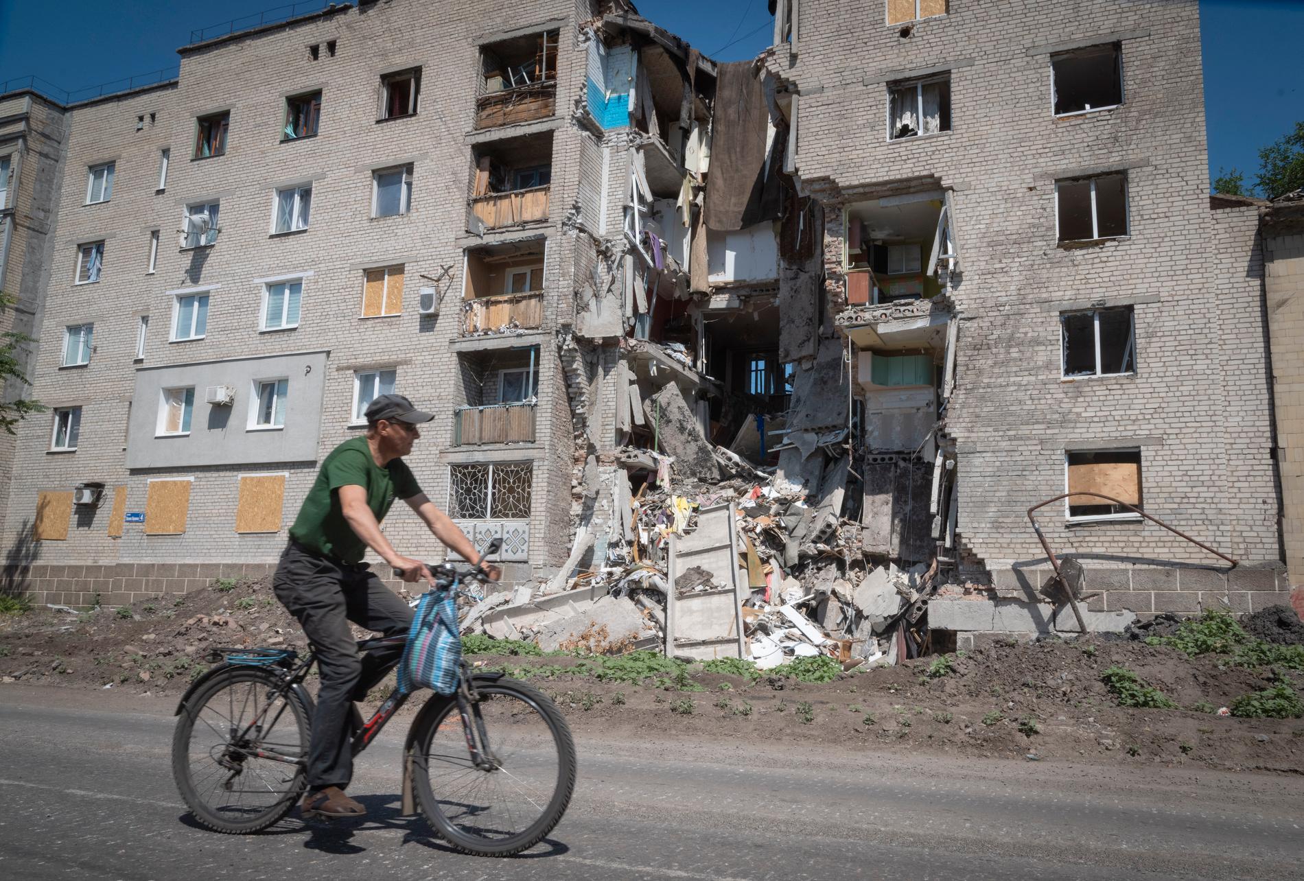 En man cyklar förbi en skadad byggnad i Bachmut. Arkivbild.