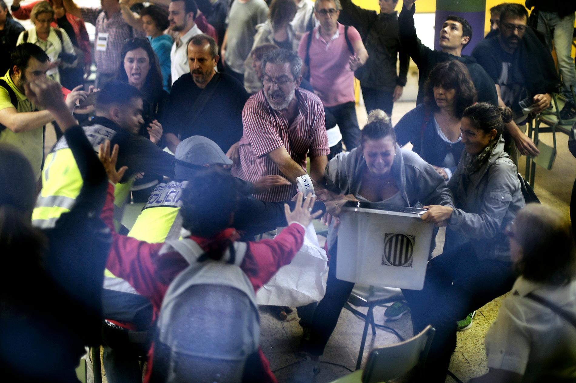 Civilklädd polis försöker ta en valurna vid Ramon Llull school i Barcelona.