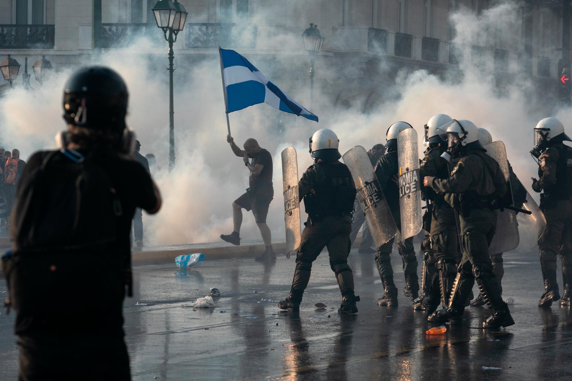 Grekisk polis använder tårgas mot anti-vaccin-demonstranter på Syntagma-torget i centrala Aten efter att tusentals människor samlats för att protestera. 