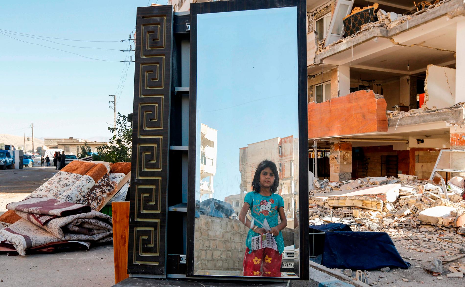 En flicka står framför en spegel i möbelhavet som har räddats ur hus som riskerar att rasa ihop.