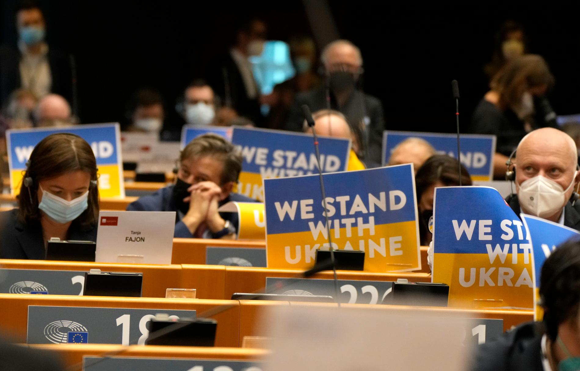 Ledamöter i EU-parlamentet visar sitt stöd för Ukraina under tisdagens extrainsatt debatt i Bryssel.
