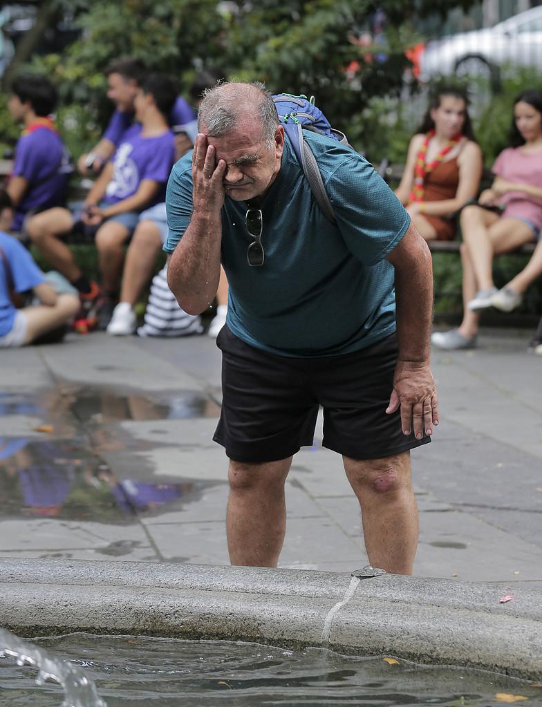 En man svalkar sig med vatten från en fontän i New York. 