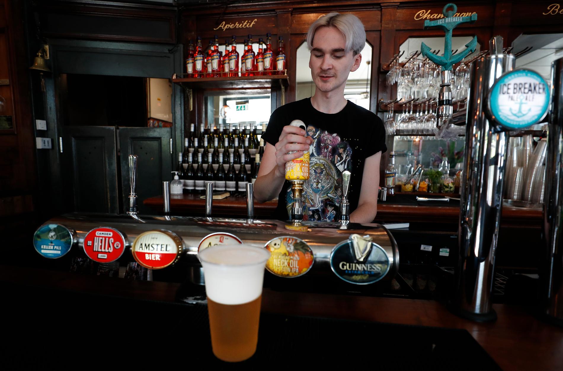 En bartender häller upp en öl på The Crabtree Pub i London på tisdagen. Handgreppen har inte gått förlorade under nedstängningen.