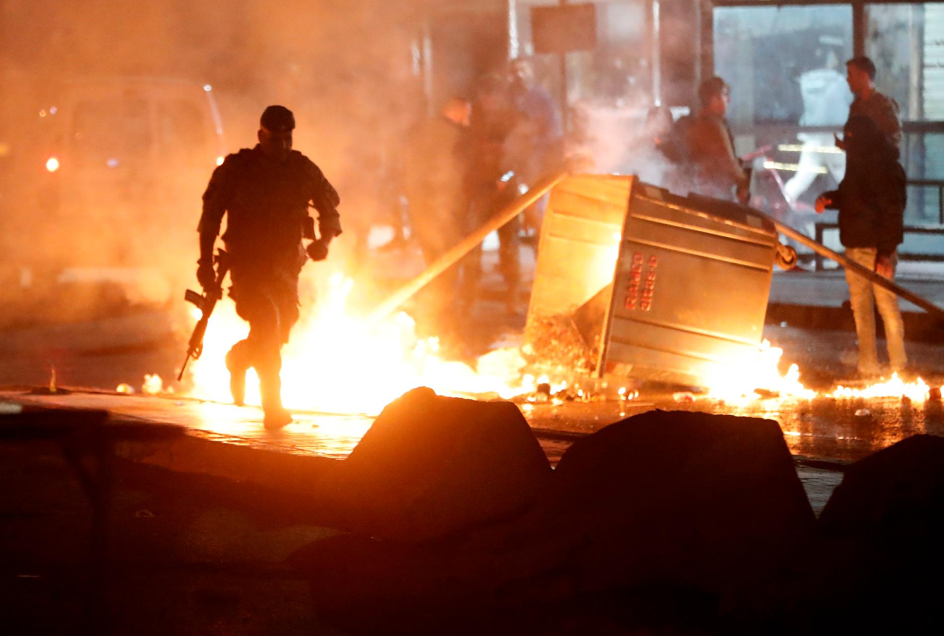 En libanesisk soldat springer bredvid en container som satts i brand av demonstranter.