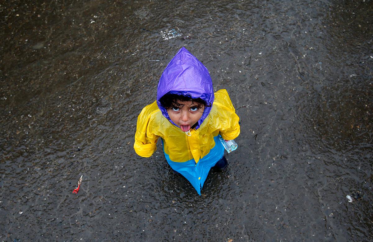 Berkasovo, Serbien: En flicka i regnjacka befinner sig tillsammans med hundratals flyktingar mellan Serbien och Kroatiens gräns. Vädret i regionen har varit dåligt och flera av flyktingarna från bland annat Syrien, Eritrea och Irak saknar regnkläder.