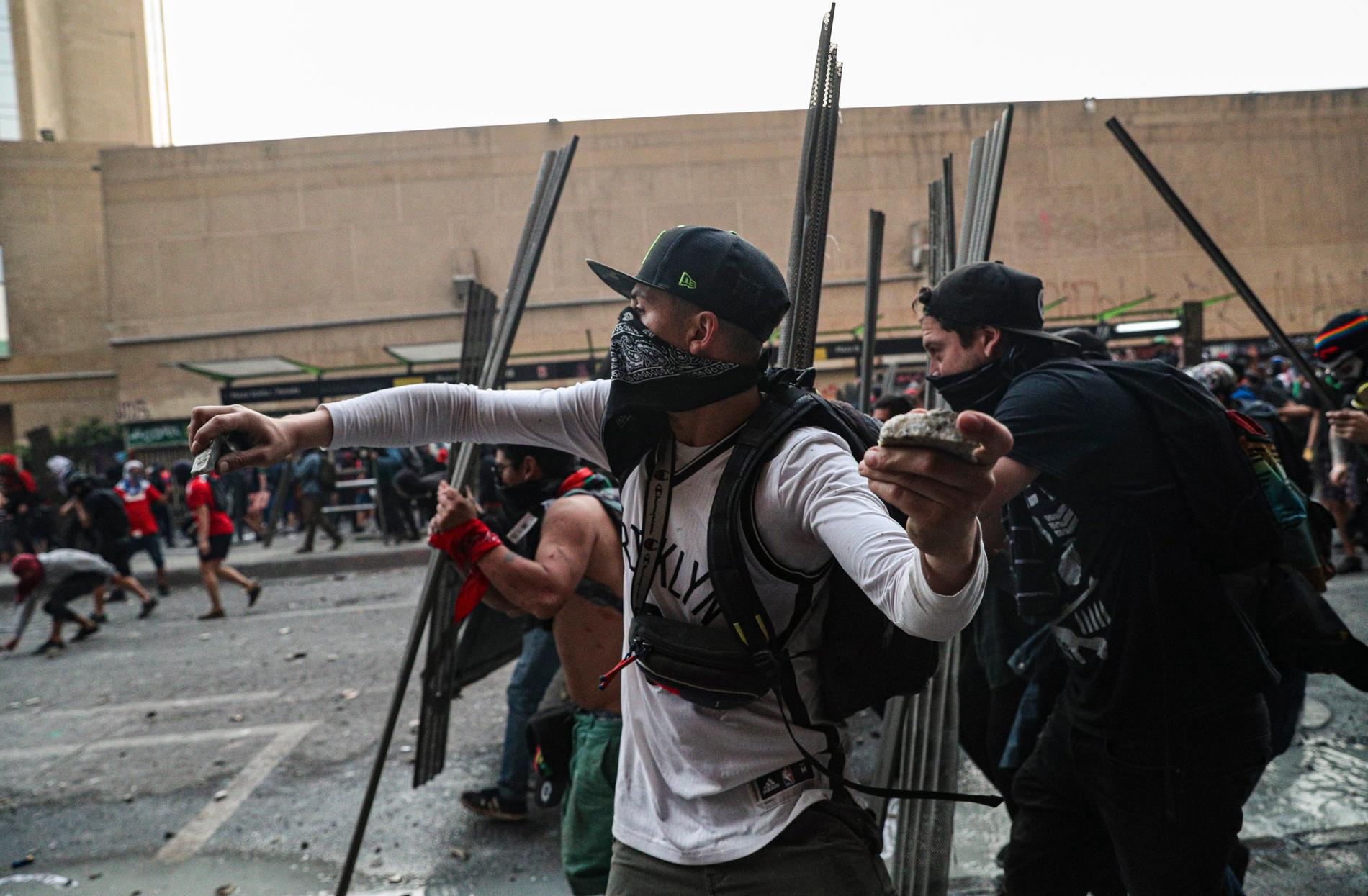 Demonstranter kastar sten mot polisen under tisdagens sammanstötningar i Santiago.