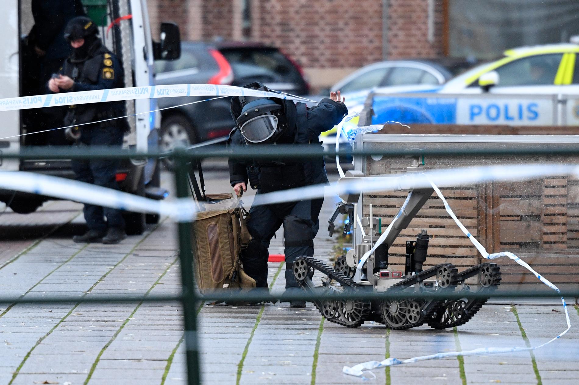 Polisens bombtekniker och bombrobot arbetar bakom avspärrningarna då man undersöker det misstänkt farliga föremålet vid en entré på Posthusplatsen.