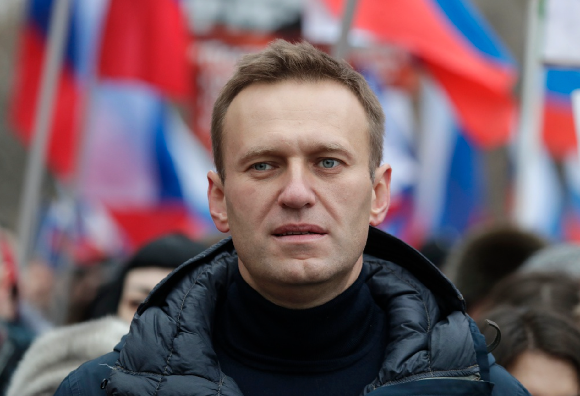 Aleksej Navalnyj med ryska flaggor i bakrgunden.