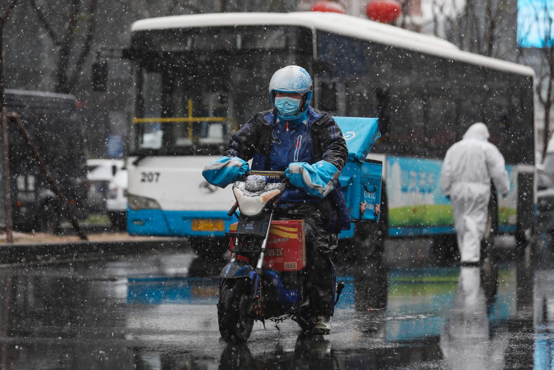 Ett bud med munskydd på väg ut med en leverans i Wuhan, centrum för virusutbrottet.