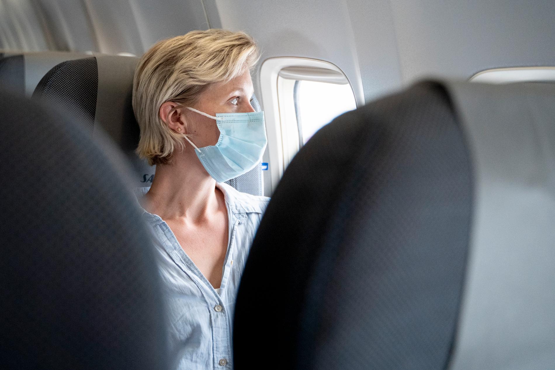 Kvinna med munskydd på flygplan. Arkivbild.