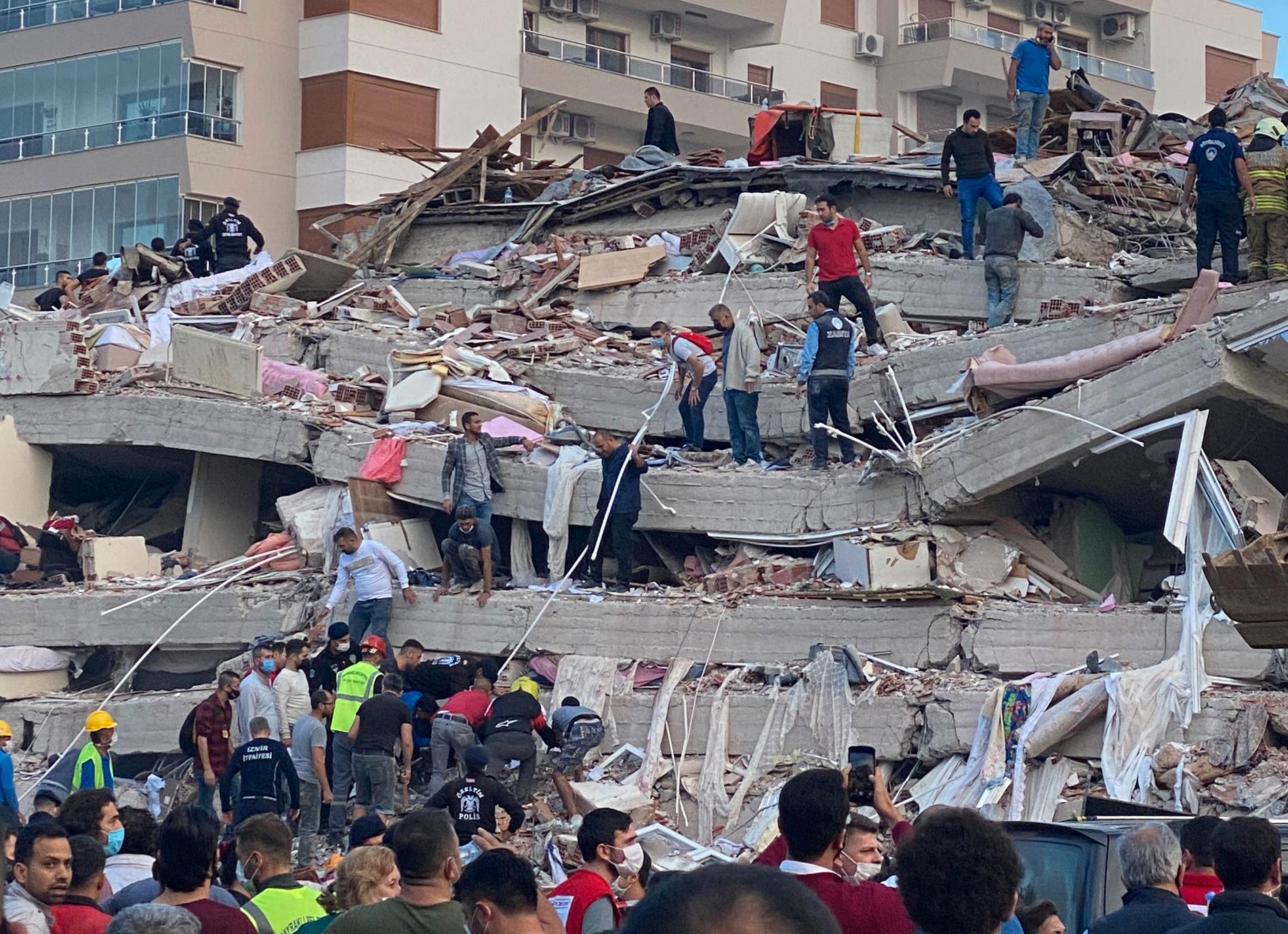 Räddningsarbetare och lokalbefolkning försöker att rädda människor från byggnader som rasat i jordbävningen.