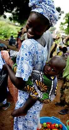 ”På väg till Sine Saloum passerar vi flera byar med bytesmarknader. Här träffar vi en kvinna som bär sitt barn i en handmålad sjal.”
