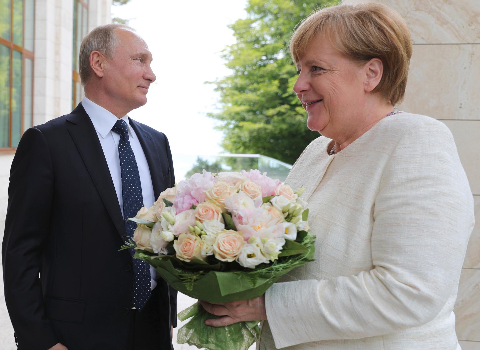 Rysslands president Vladimir Putin hälsade Tysklands förbundskansler Angela Merkel med en bukett blommor när hon besökte ryska semesterorten Sotji i maj. Arkivbild.