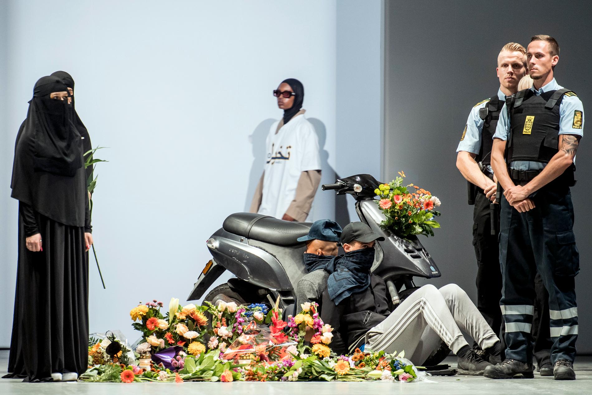 Modeller iförda niqab och polisuniformer på catwalken i Köpenhamn. Bakom modeshowen står den Iranfödde designern Reza Etamadi.