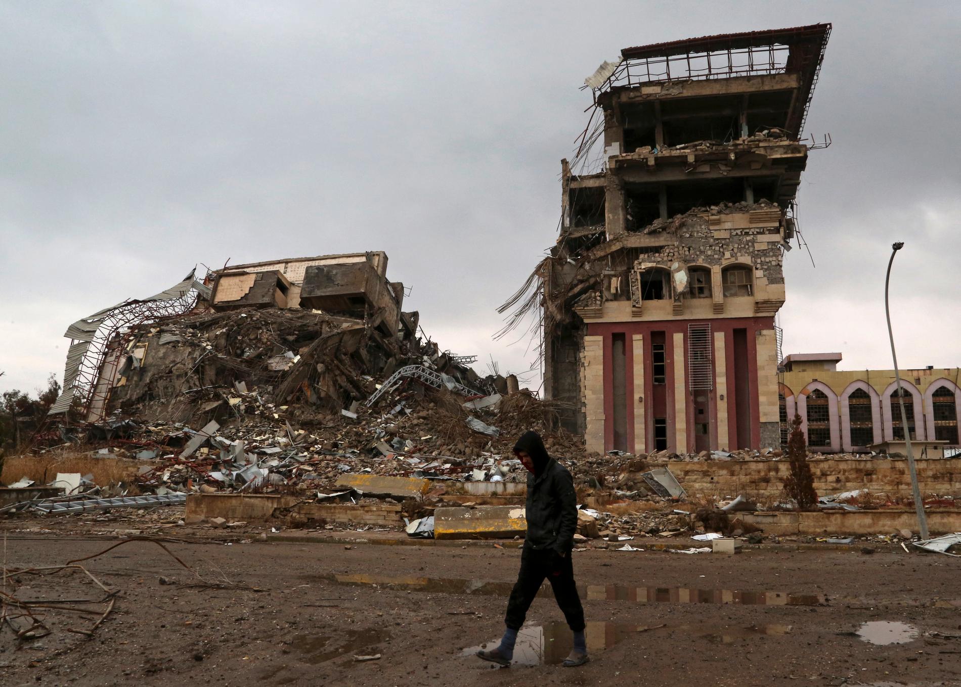 En student framför universitetet i den irakiska staden Mosul, vars byggnader förstördes i striderna om staden.