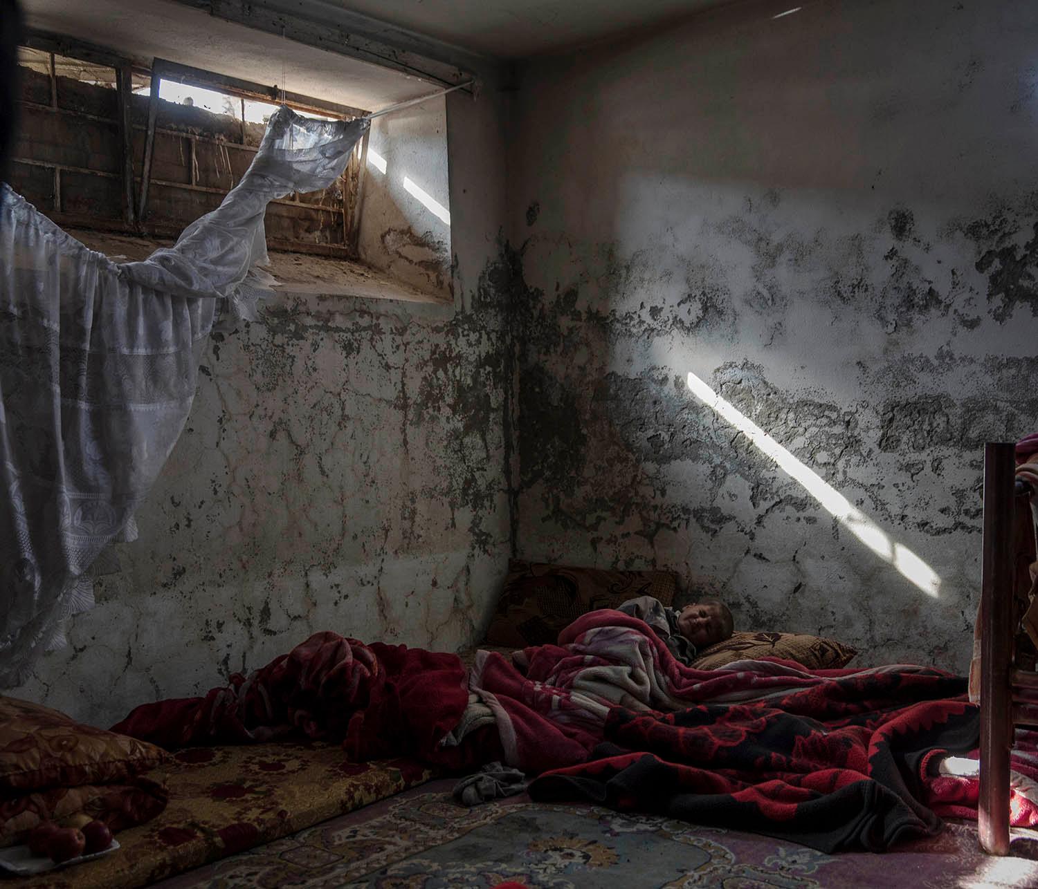 Ali ligger i källaren på familjens sönderbombade hus i stadsdelen Galzani. De bor 23 personer i samma rum. Vi ska bygga upp vårar hem igen. Det viktiga är att vi är fria från IS nu, säger Alis pappa. 