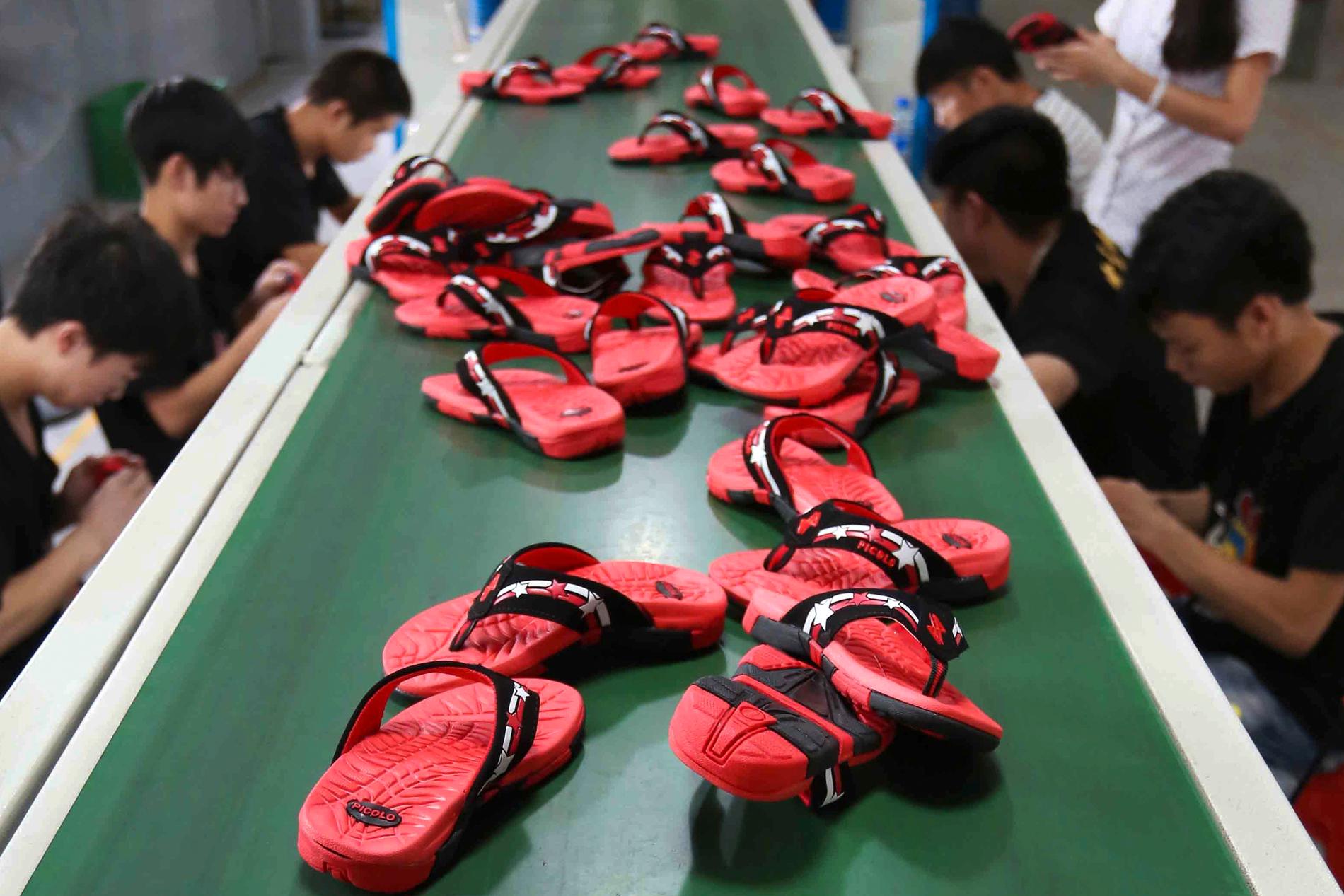 Kinesiska arbetare vid ett löpband med tofflor på en fabrik i Jinjang. 