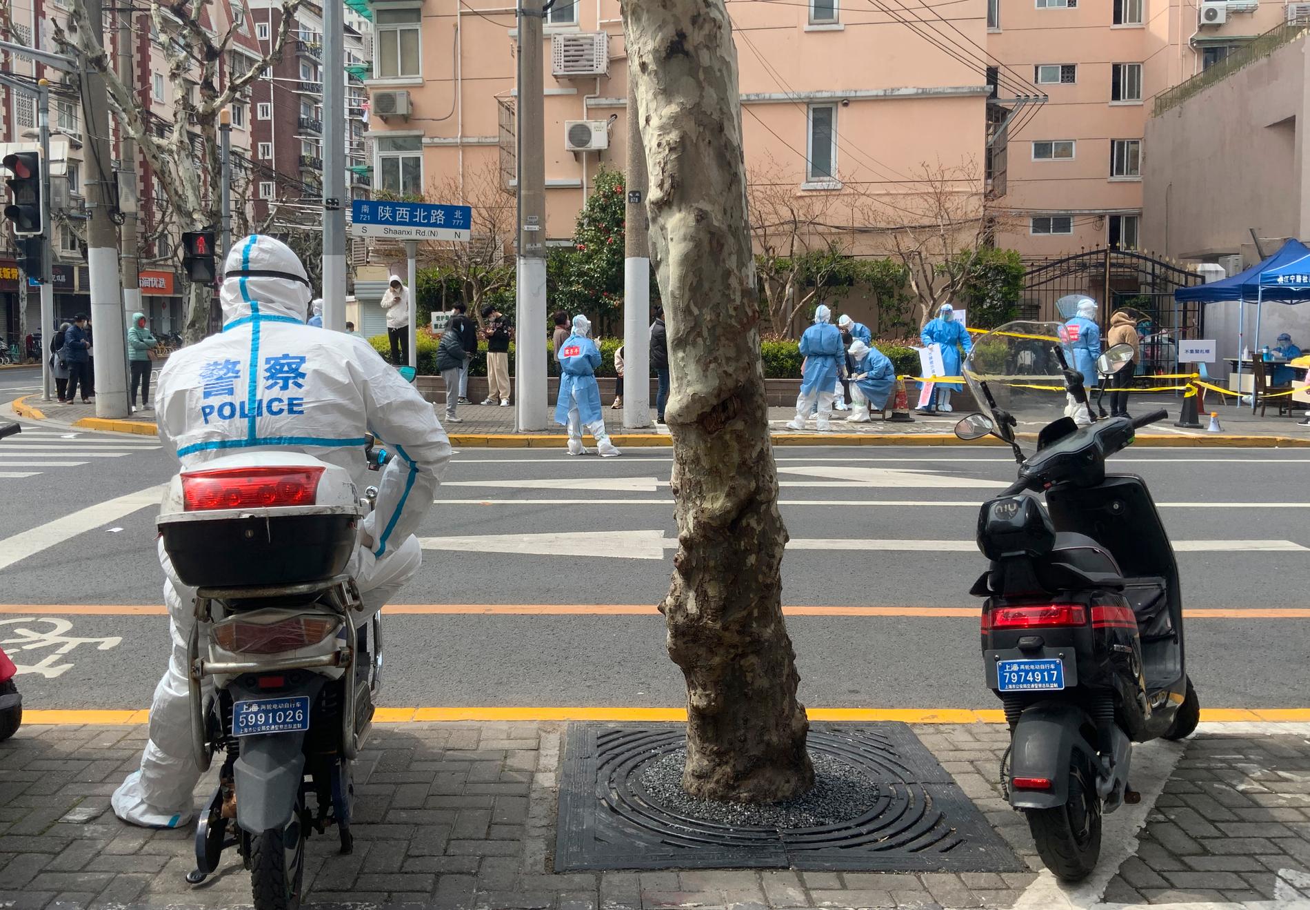 En polis i skyddsdräkt bevakar coronatestningen av invånare i västra Shanghai som gick in i lockdown 1 april.